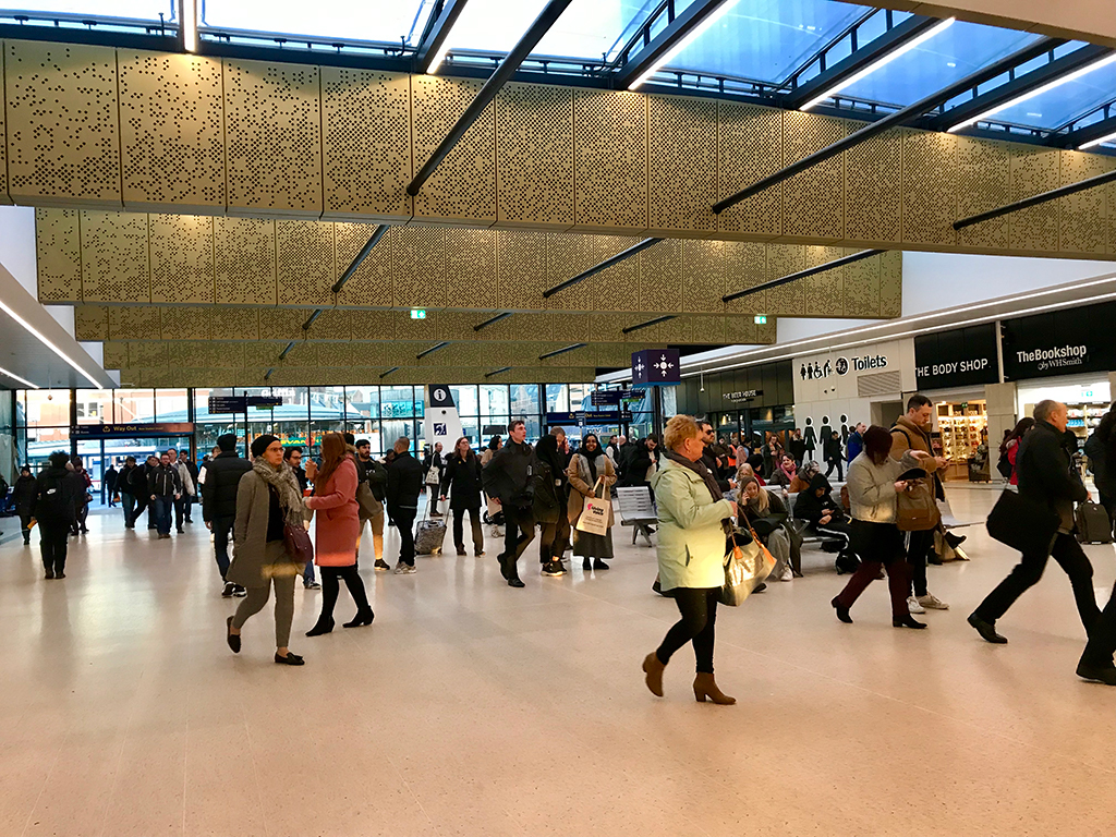 Inside Leeds Station, new gold roofing is above commuters in the new space.