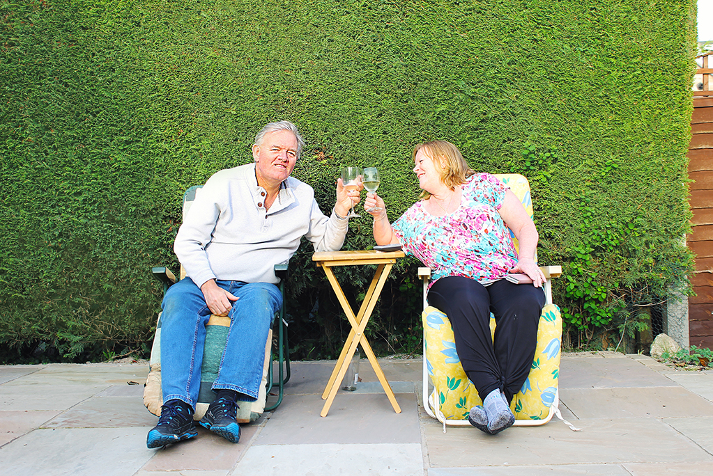 Couple relax in garden with wine